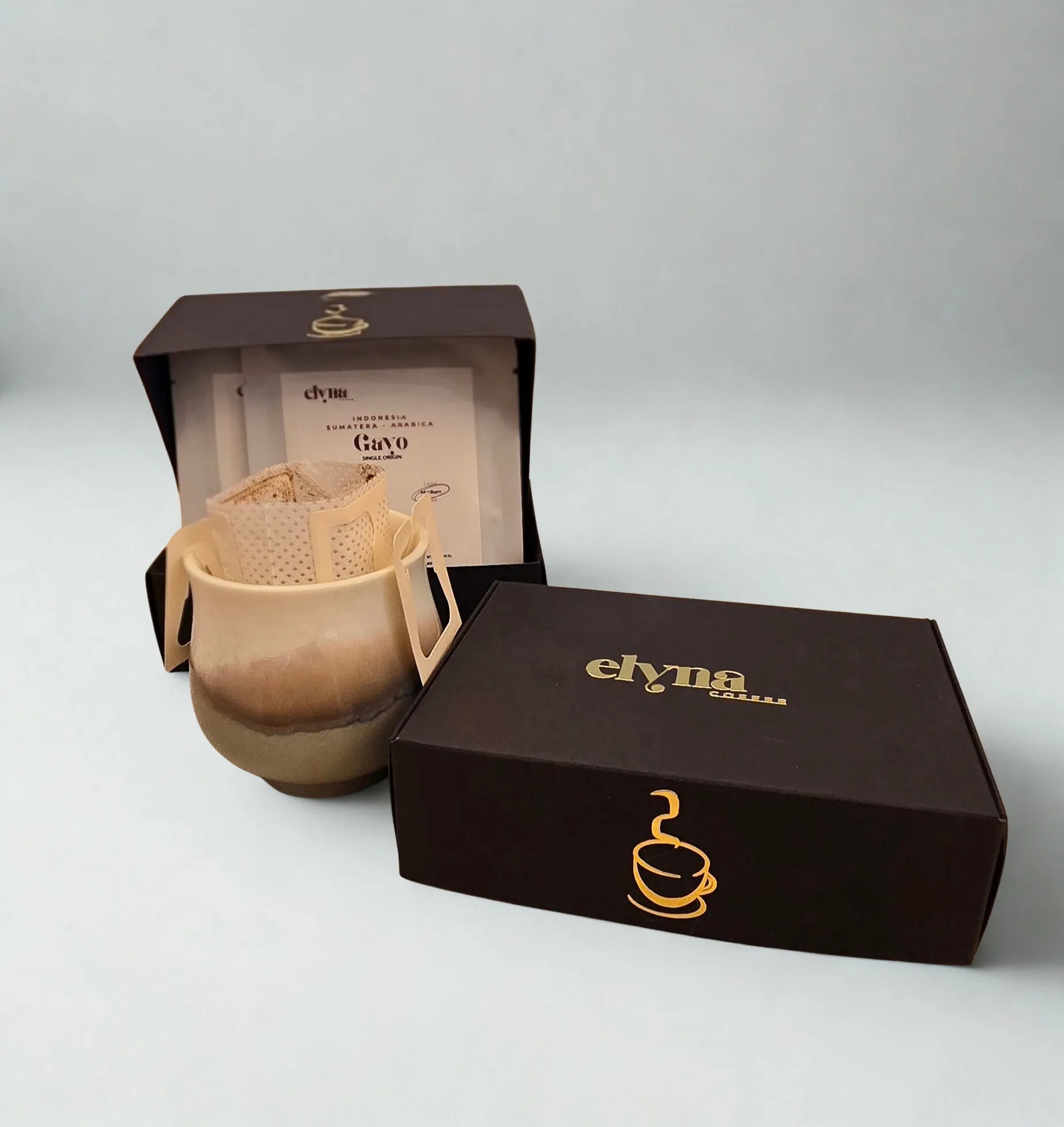 Ceramic mug with filter and Elyna branded box on a gray background