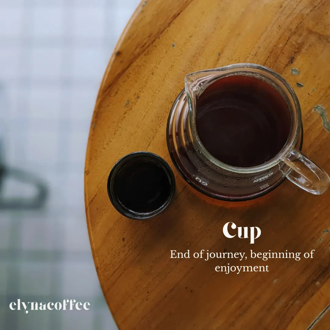Glass carafe with coffee on a wooden surface, text 'Cup End of journey, beginning of enjoyment' displayed.